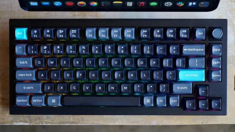 Compact mechanical keyboard with dark keycaps, rainbow backlighting, bright turquoise escape and enter keys, media and function row, side navigation cluster, and a volume knob on the top right