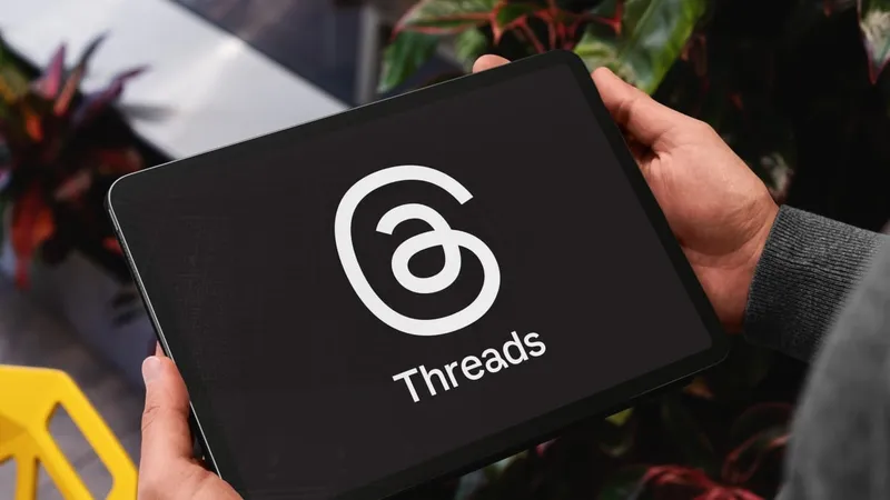 Close-up of businessman holding tablet displaying threads app logo, suggesting connection and communication in professional setting