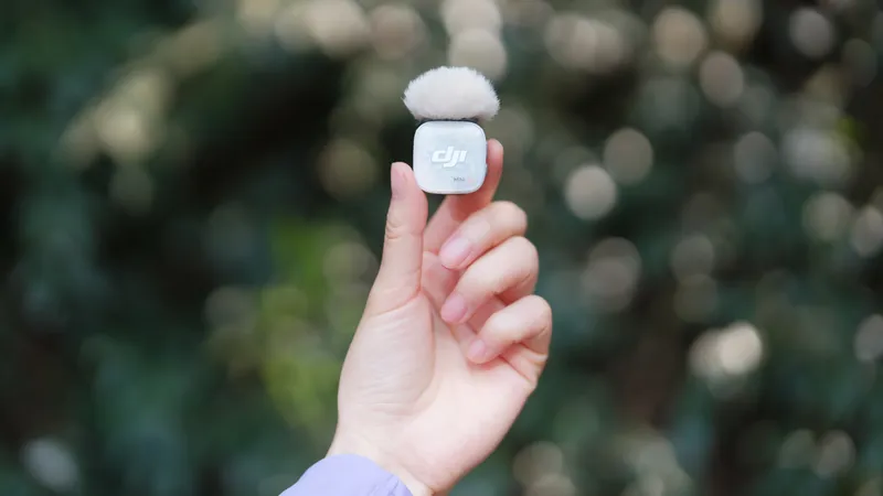 A hand holding up a DJI Mic Mini 2S with a fluffy windscreen attached to it.