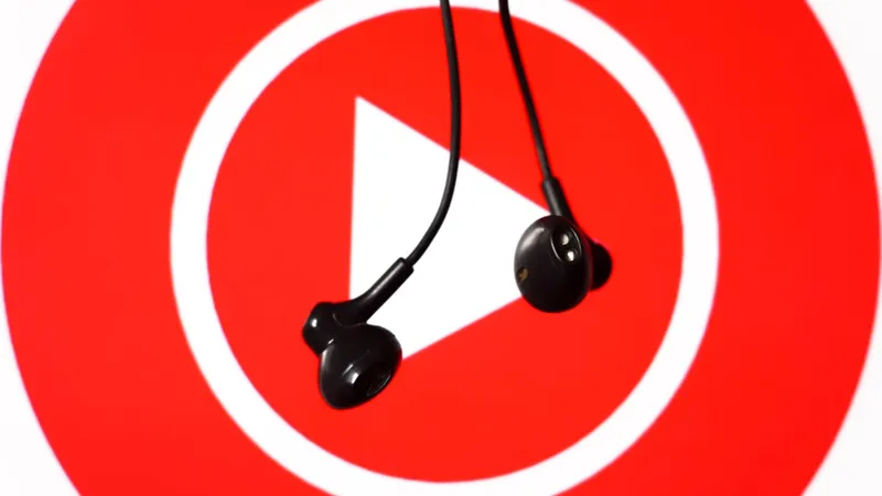 A pair of earbuds dangling in front of a large YouTube Music logo.