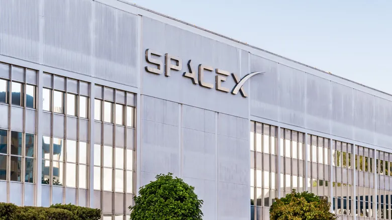 A building with grey siding and windows bears the SpaceX logo.