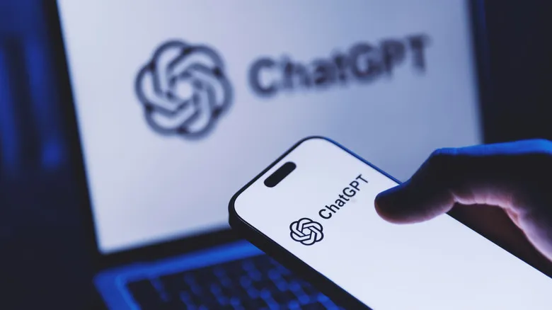 ChatGPT logo shown clearly on a smartphone in the foreground and blurred on a laptop screen in the background