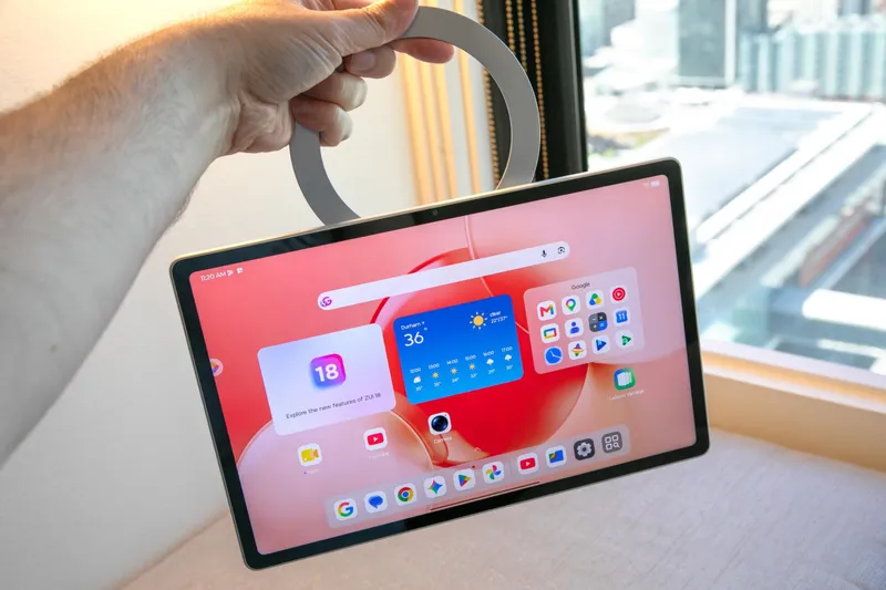 The Lenovo Tab Plus Gen 2 tablet hanging from its kickstand held in a person’s hand.